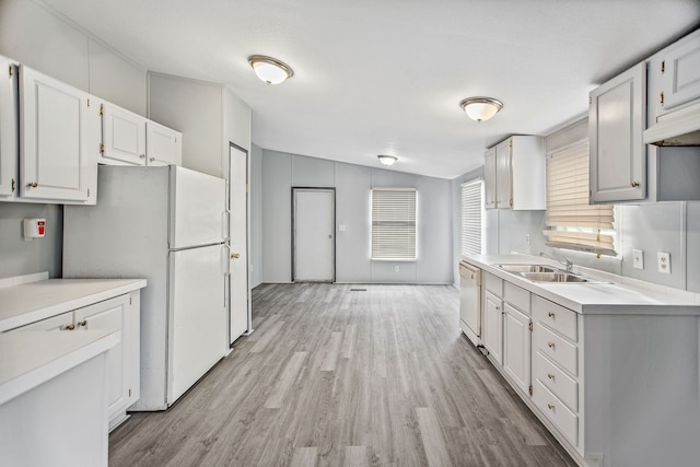 kitchen with white appliances, vaulted ceiling, sink, light hardwood / wood-style flooring, and white cabinetry