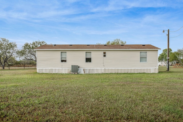 rear view of house featuring a lawn and central AC unit