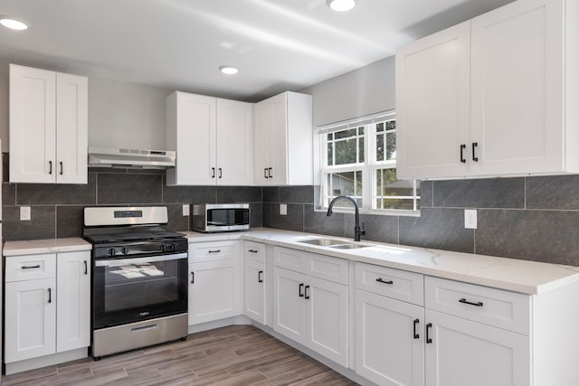 kitchen featuring ventilation hood, light wood-type flooring, white cabinetry, and stainless steel appliances