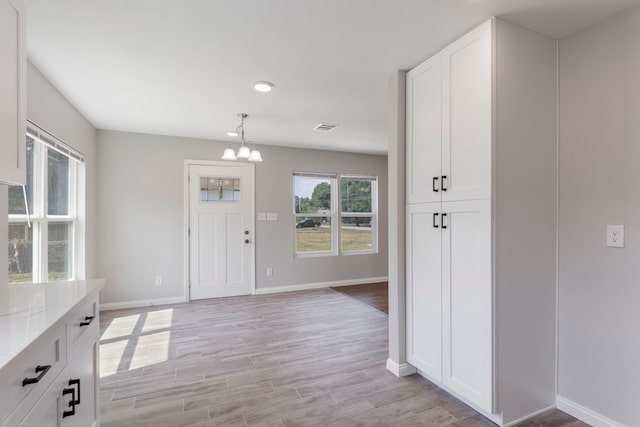 entrance foyer with light hardwood / wood-style floors and a notable chandelier