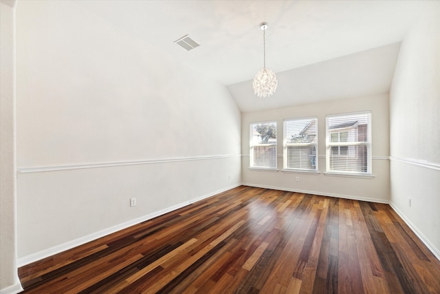 spare room featuring dark hardwood / wood-style floors, lofted ceiling, and a chandelier