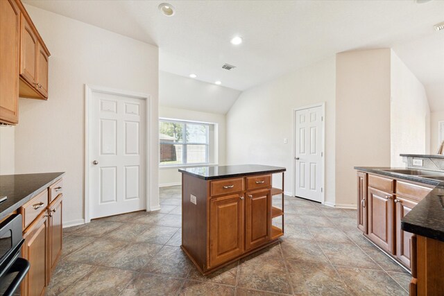 kitchen with vaulted ceiling, sink, dark stone countertops, dishwasher, and a center island