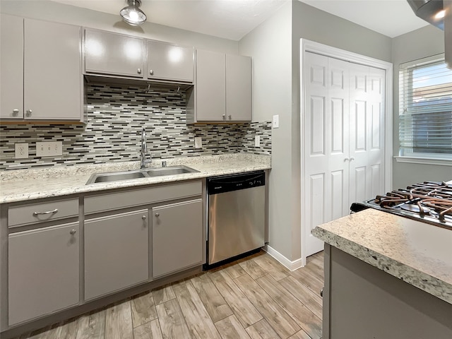 kitchen with light wood-type flooring, backsplash, gray cabinetry, sink, and dishwasher