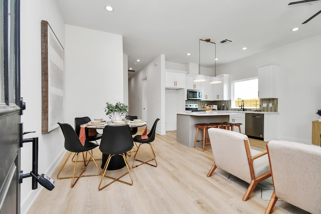 dining room featuring ceiling fan, sink, and light hardwood / wood-style floors