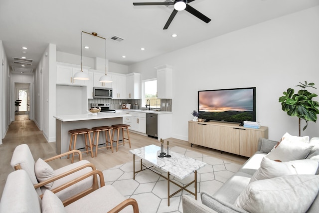 living room featuring ceiling fan, sink, and light hardwood / wood-style flooring