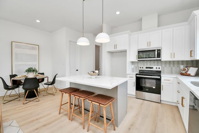 kitchen with white cabinetry, hanging light fixtures, a kitchen island, and stainless steel appliances