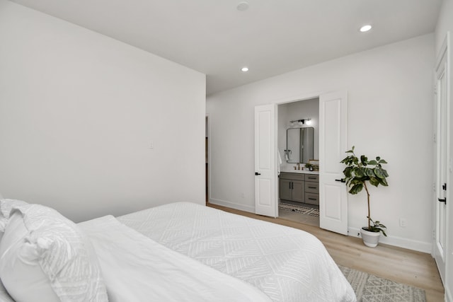 bedroom featuring light wood-type flooring and connected bathroom