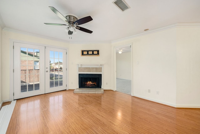 unfurnished living room with ceiling fan, french doors, crown molding, light hardwood / wood-style floors, and a fireplace