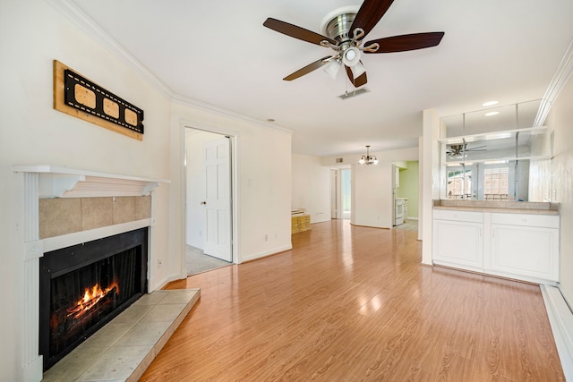 unfurnished living room with ceiling fan, crown molding, a fireplace, and light hardwood / wood-style flooring