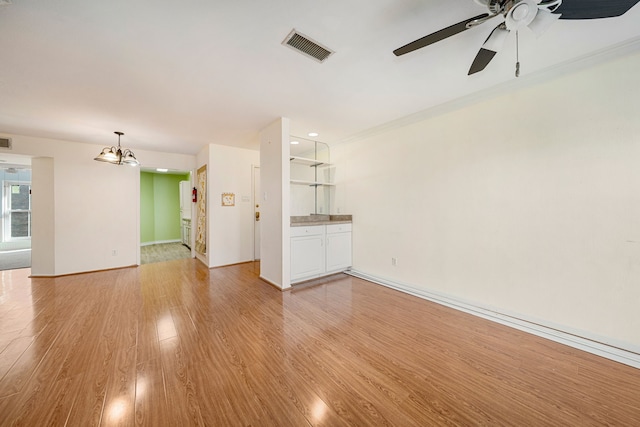 unfurnished living room featuring crown molding, ceiling fan with notable chandelier, and light wood-type flooring