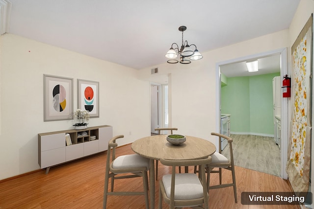 dining area featuring light hardwood / wood-style floors and an inviting chandelier