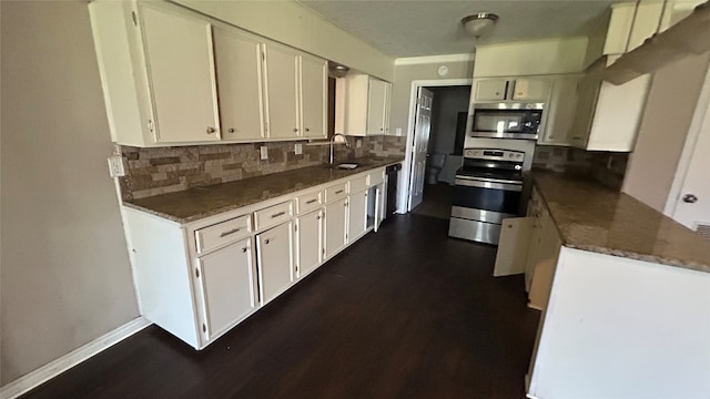 kitchen featuring sink, dark wood-type flooring, dark stone countertops, white cabinets, and appliances with stainless steel finishes