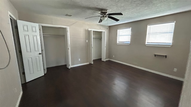 unfurnished bedroom with dark hardwood / wood-style floors, ceiling fan, and multiple closets