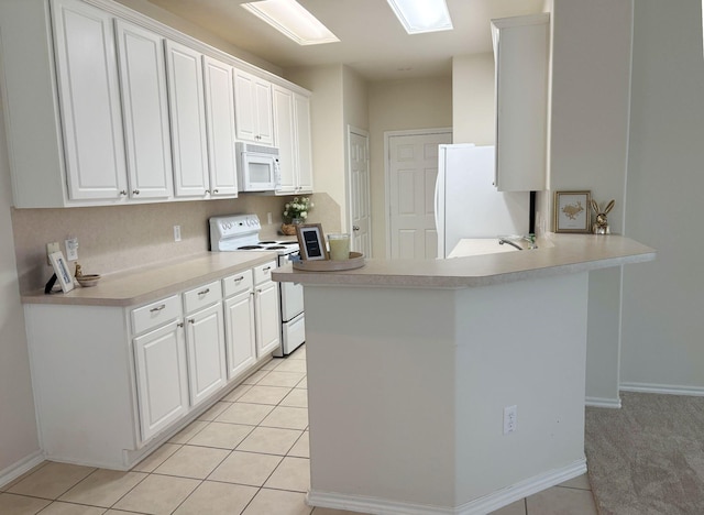 kitchen featuring a peninsula, white appliances, and white cabinets