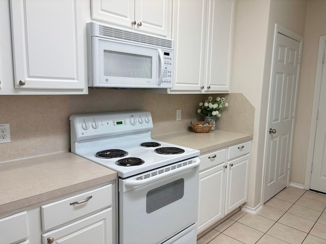 kitchen featuring light countertops, white appliances, light tile patterned flooring, and white cabinetry