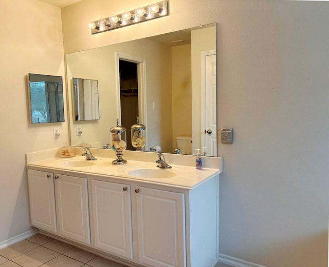 full bath featuring double vanity, a sink, toilet, and tile patterned floors