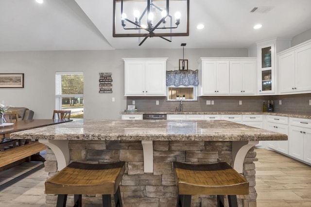 kitchen featuring pendant lighting, light stone counters, and a breakfast bar