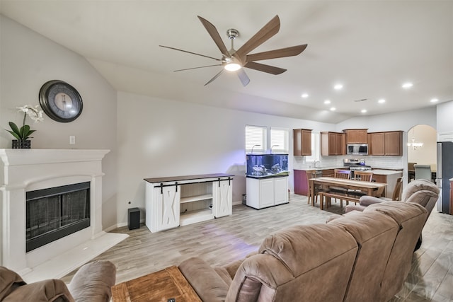 living room with ceiling fan, light hardwood / wood-style floors, lofted ceiling, and sink