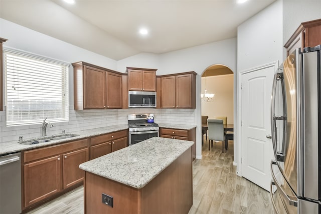 kitchen with a center island, sink, tasteful backsplash, light hardwood / wood-style floors, and stainless steel appliances