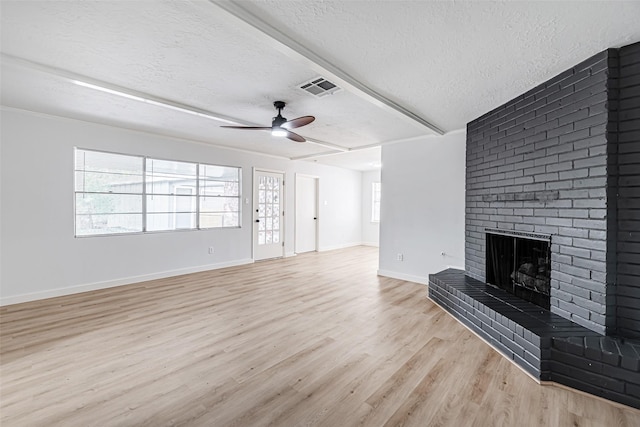 unfurnished living room featuring a brick fireplace, a textured ceiling, ceiling fan, and light hardwood / wood-style floors