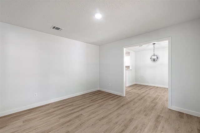 unfurnished room featuring a textured ceiling and light hardwood / wood-style floors