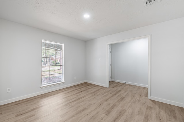 spare room featuring a textured ceiling and light hardwood / wood-style flooring