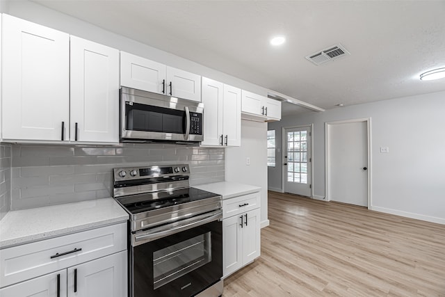 kitchen with white cabinets, stainless steel appliances, light stone counters, and tasteful backsplash