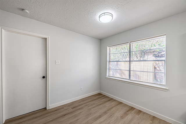 unfurnished room with a textured ceiling, light hardwood / wood-style floors, and a wealth of natural light