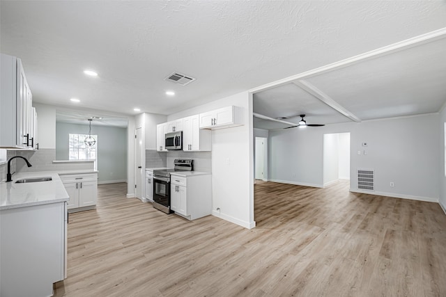 kitchen with tasteful backsplash, stainless steel appliances, white cabinets, decorative light fixtures, and sink