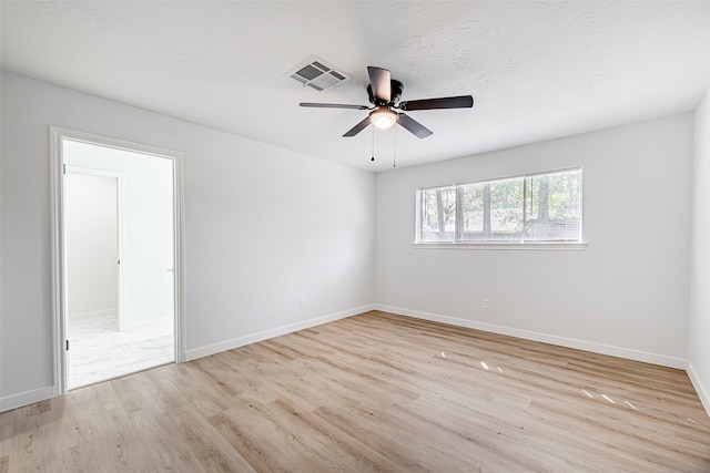 spare room featuring light wood-type flooring, ceiling fan, and a textured ceiling