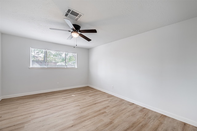 spare room featuring a textured ceiling, light wood-type flooring, and ceiling fan