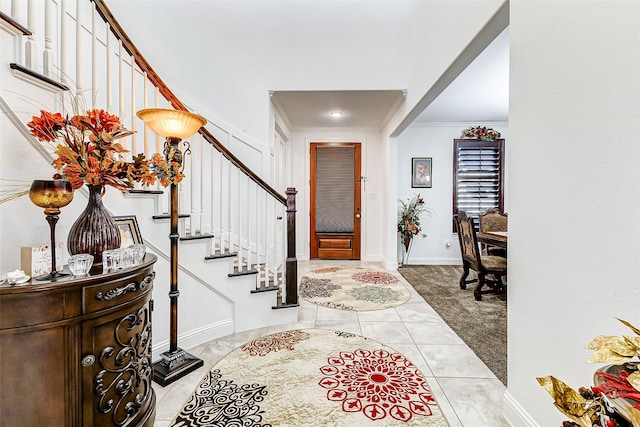 entryway with ornamental molding and light tile patterned floors