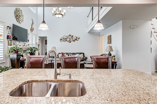 kitchen featuring sink, pendant lighting, a notable chandelier, and light stone countertops