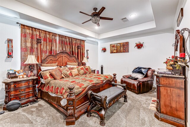 carpeted bedroom featuring ceiling fan and a tray ceiling