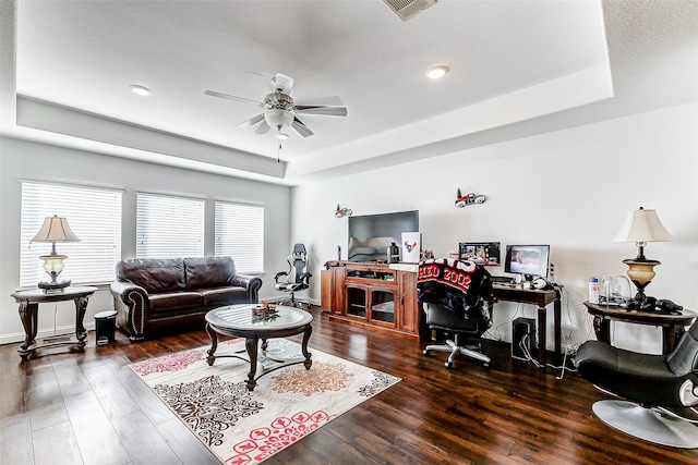 living room with ceiling fan, dark wood-type flooring, and a raised ceiling