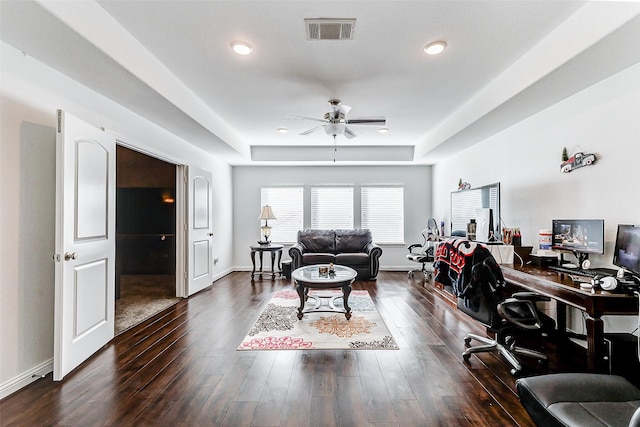 office area featuring ceiling fan, dark wood-type flooring, and a raised ceiling