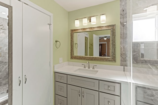 bathroom with a tile shower, ceiling fan, and vanity