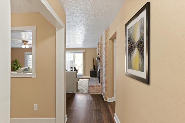 hall with dark wood-type flooring and a textured ceiling