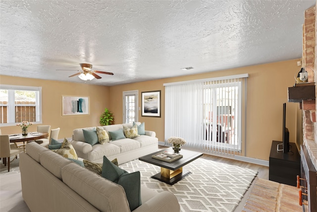 living room with ceiling fan, light hardwood / wood-style flooring, and a textured ceiling