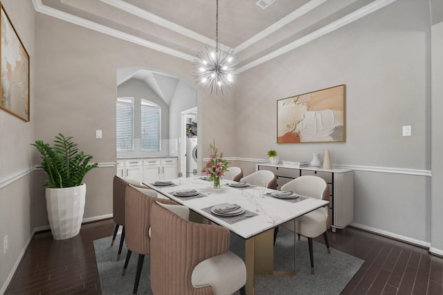 dining space featuring washer / dryer, crown molding, dark hardwood / wood-style floors, and an inviting chandelier