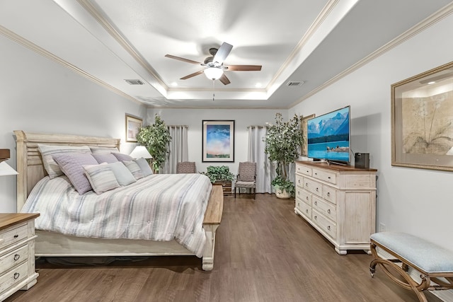 bedroom with dark hardwood / wood-style flooring, a raised ceiling, ceiling fan, and ornamental molding