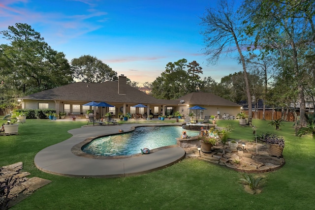 pool at dusk with a yard and a patio