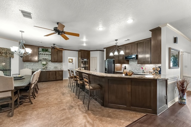 kitchen featuring decorative light fixtures, light stone counters, crown molding, and fridge with ice dispenser