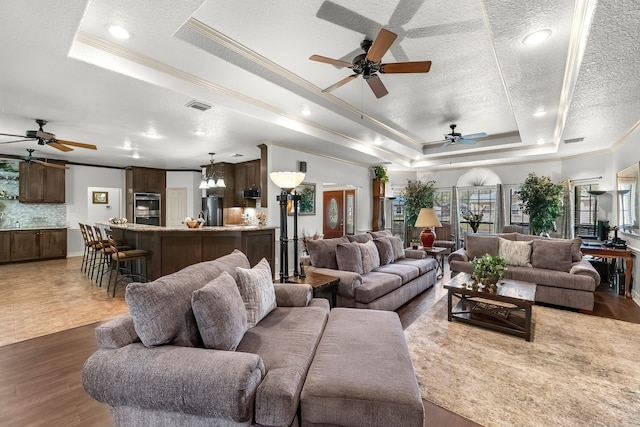 living room with ornamental molding, a textured ceiling, dark hardwood / wood-style floors, and a tray ceiling