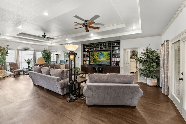 living room with dark hardwood / wood-style flooring, ceiling fan, and a raised ceiling