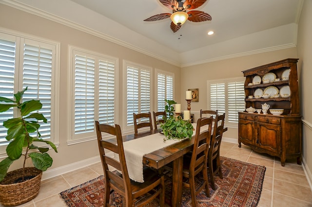 tiled dining area with ceiling fan and crown molding