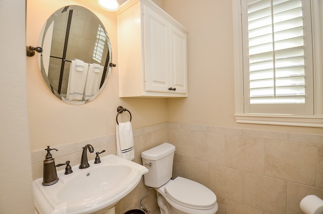 bathroom featuring toilet, tile walls, and sink