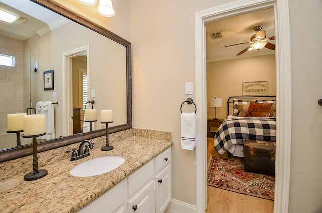 bathroom with wood-type flooring, vanity, ceiling fan, and crown molding