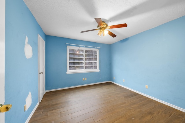 empty room with a textured ceiling, ceiling fan, and dark wood-type flooring