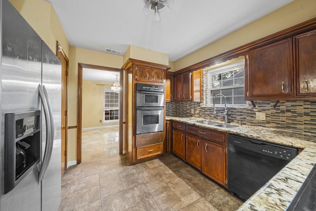 kitchen featuring an inviting chandelier, sink, tasteful backsplash, light stone counters, and stainless steel appliances